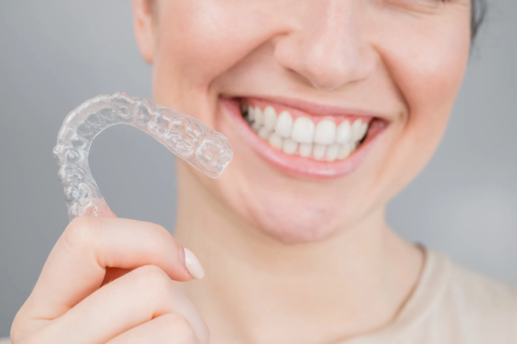 Smiling woman holding clear Invisalign aligner - SpringLake Dental Woodland